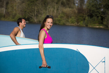 Young couple with SUP Boards in front of lake - JTLF00127