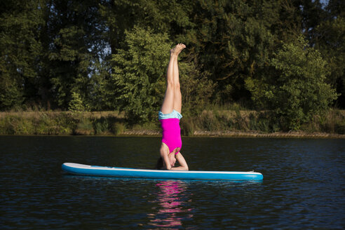 Young woman doing headstand on SUP Board - JTLF00128