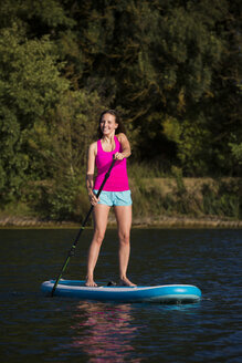 Glückliche junge Frau auf SUP Board - JTLF00129