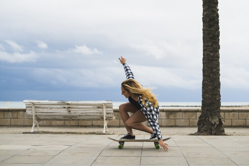 Junge Frau balanciert auf einem Skateboard - KKAF00044