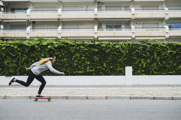 Junge Frau, die auf der Straße Skateboard fährt - KKAF00057