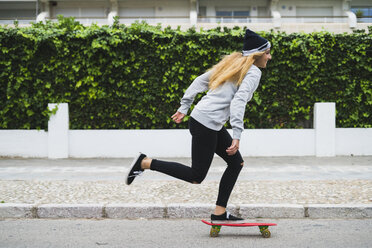 Junge Frau, die auf der Straße Skateboard fährt - KKAF00058