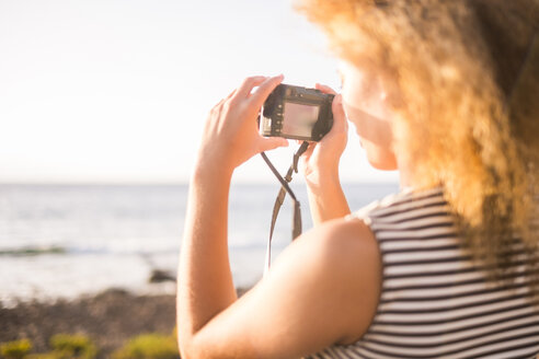 Junge Frau fotografiert das Meer mit einer Digitalkamera - SIPF01063