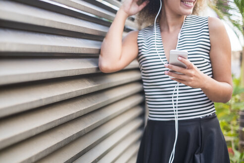 Junge Frau mit Smartphone hört Musik, Teilansicht - SIPF01069