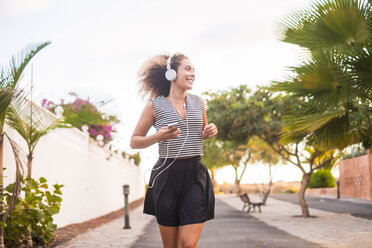 Spanien, junge Frau beim Joggen mit Smartphone und Kopfhörern - SIPF01070