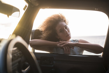 Porträt einer jungen Frau, die sich an ein Autofenster lehnt und hineinschaut - SIPF01071