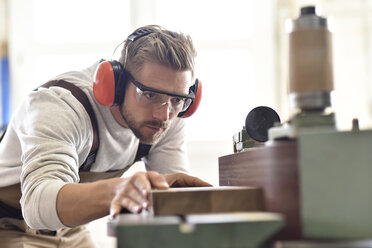 Schreiner mit Bandschleifer in seiner Werkstatt - LYF00666