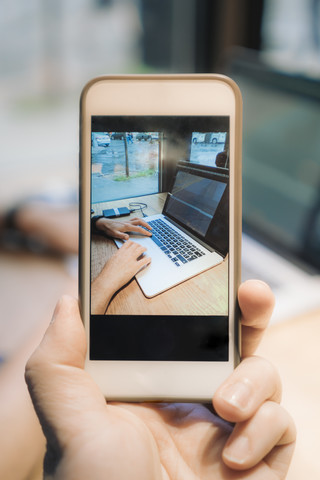 Handybild eines Mannes mit Laptop, lizenzfreies Stockfoto