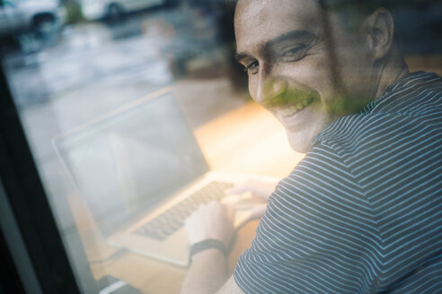 Lächelnder Mann mit Laptop - GIOF01595