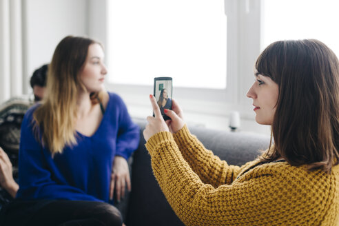 Junge Frau, die ein Smartphone-Foto von ihrer Freundin macht - LCUF00080