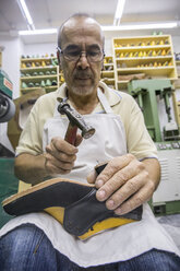 Schuhmacher bei der Arbeit mit dem Hammer an einem Schuh in seiner Werkstatt - ABZF01480