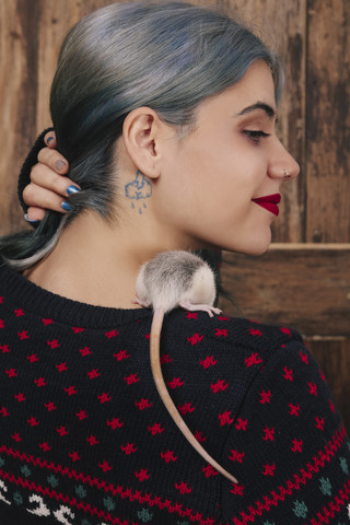 Young woman with pet rat on her shoulder wearing patterned knit pullover stock photo