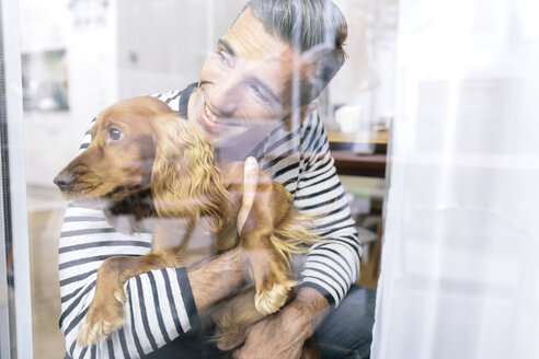 Mann mit Hund zu Hause und Blick aus dem Fenster - MADF01177