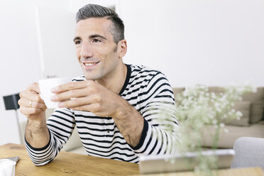 Smiling man at home holding coffee cup - MADF01184