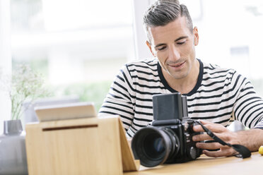 Man at home with camera and tablet - MADF01194