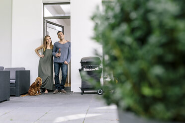 Lächelndes Paar mit Hund vor der Terrassentür - MADF01202