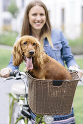 Lächelnde Frau mit Hund im Fahrradkorb - MADF01211