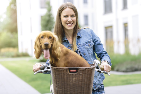 Lächelnde Frau mit Hund im Fahrradkorb, lizenzfreies Stockfoto