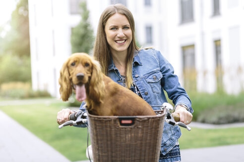 Lächelnde Frau mit Hund im Fahrradkorb - MADF01212