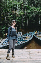 Peru, Tambopata, Woman with muddy rubber boots standing on jetty at Amazon river - GEMF01213