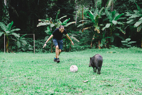 Peru, Mann spielt Fußball mit einem Pekari - GEMF01224