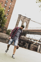 USA, New York, junger Mann spielt Basketball auf einem Platz im Freien - UUF09120