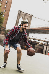 USA, New York, junger Mann spielt Basketball auf einem Platz im Freien - UUF09121