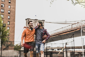 USA, New York, zwei glückliche junge Männer auf einem Basketballplatz im Freien - UUF09122