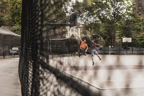 Zwei junge Männer spielen Basketball auf einem Platz im Freien, lizenzfreies Stockfoto