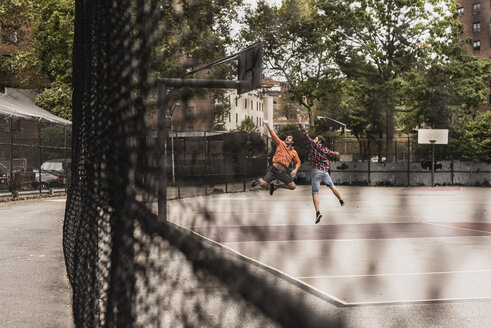 Zwei junge Männer spielen Basketball auf einem Platz im Freien - UUF09132