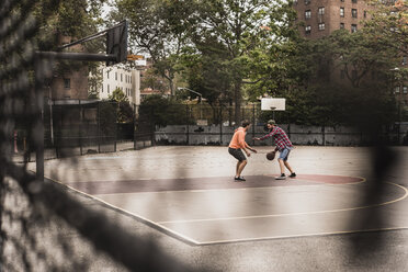 Two young men playing basketball on an outdoor court - UUF09133
