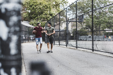 Two friends walking with basketball outdoors - UUF09140