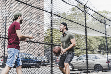 Zwei junge Männer mit Basketball haben Spaß auf einem Platz im Freien - UUF09146