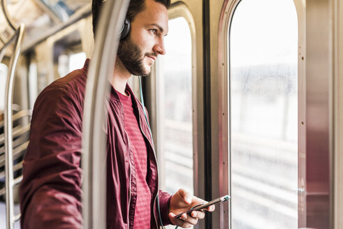 Young man in subway wearing headphones - UUF09159