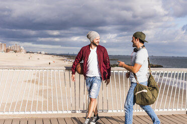 USA, New York City, zwei Freunde gehen auf einer Brücke auf Coney Island spazieren - UUF09171