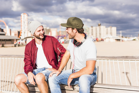 USA, New York City, zwei Freunde sitzen auf einer Brücke auf Coney Island, lizenzfreies Stockfoto