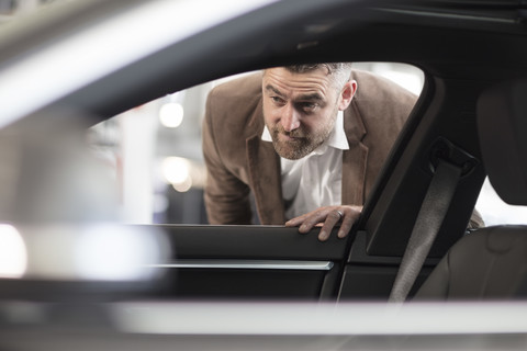 Mann schaut im Autohaus ins Auto, lizenzfreies Stockfoto