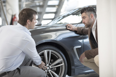 Autohändler im Gespräch mit einem Kunden im Ausstellungsraum, lizenzfreies Stockfoto