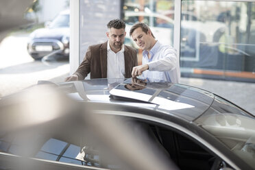 Car dealer talking to client at car dealership - ZEF11531