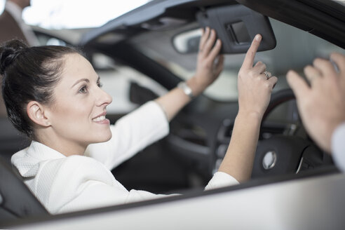 Lächelnde Frau im Auto sitzend im Autohaus - ZEF11544