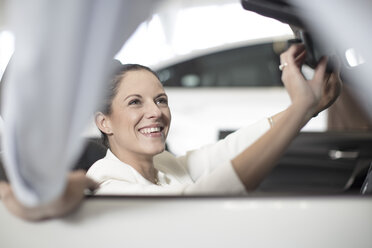 Lächelnde Frau im Auto sitzend im Autohaus - ZEF11545