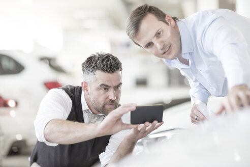 Mann fotografiert mit Handy im Autohaus - ZEF11561