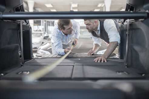 Autohändler misst den Kofferraum eines Autos im Autohaus - ZEF11566