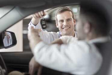 Car dealer handing over key to man at car dealership - ZEF11572