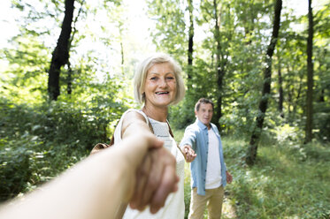 Porträt einer glücklichen älteren Frau Hand in Hand mit zwei Männern in der Natur - HAPF01059