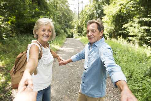 Älteres Paar hält Hände mit dritter Person auf Waldweg - HAPF01073