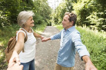 Älteres Paar hält Hände mit dritter Person auf Waldweg - HAPF01074