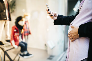 Schwangere Frau mit Mobiltelefon am Schaufenster - JRFF01008