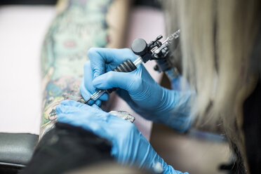 Female tattoo artist tattooing a leg - ZEF11594