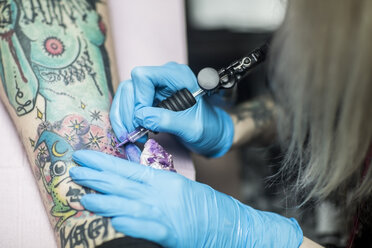 Female tattoo artist tattooing a leg - ZEF11596